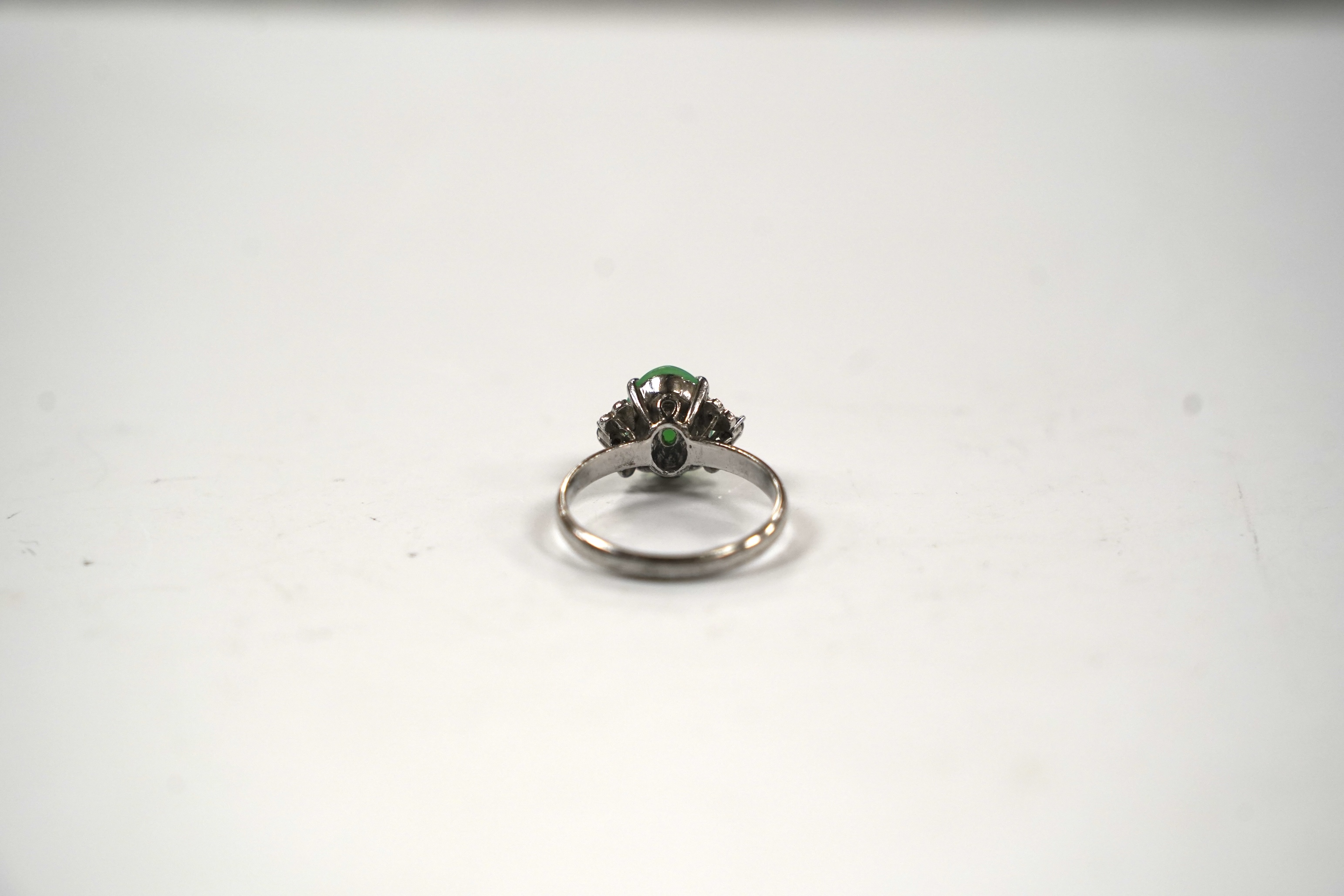 A modern 18k white metal and single stone cabochon jade and six stone diamond chip set ring, size O, gross weight 3 grams.